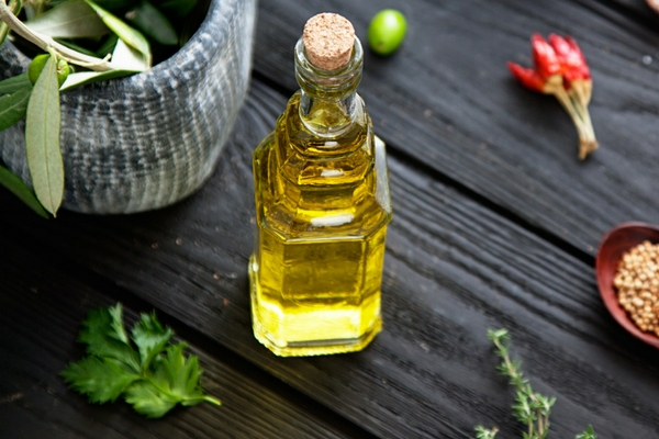 Bottle of olive oil on the bench with herbs