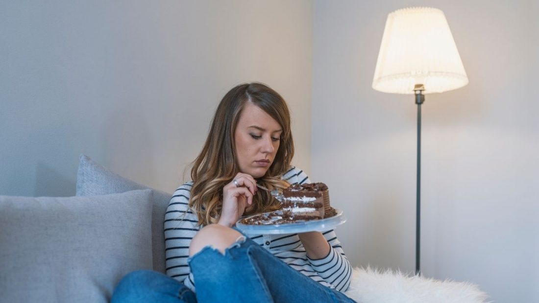 Sad woman eating chocolate cake on the lounge