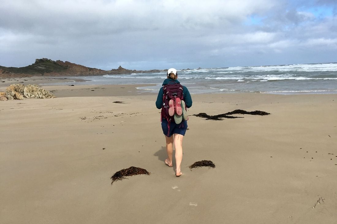 Walking along the beach with backpack on